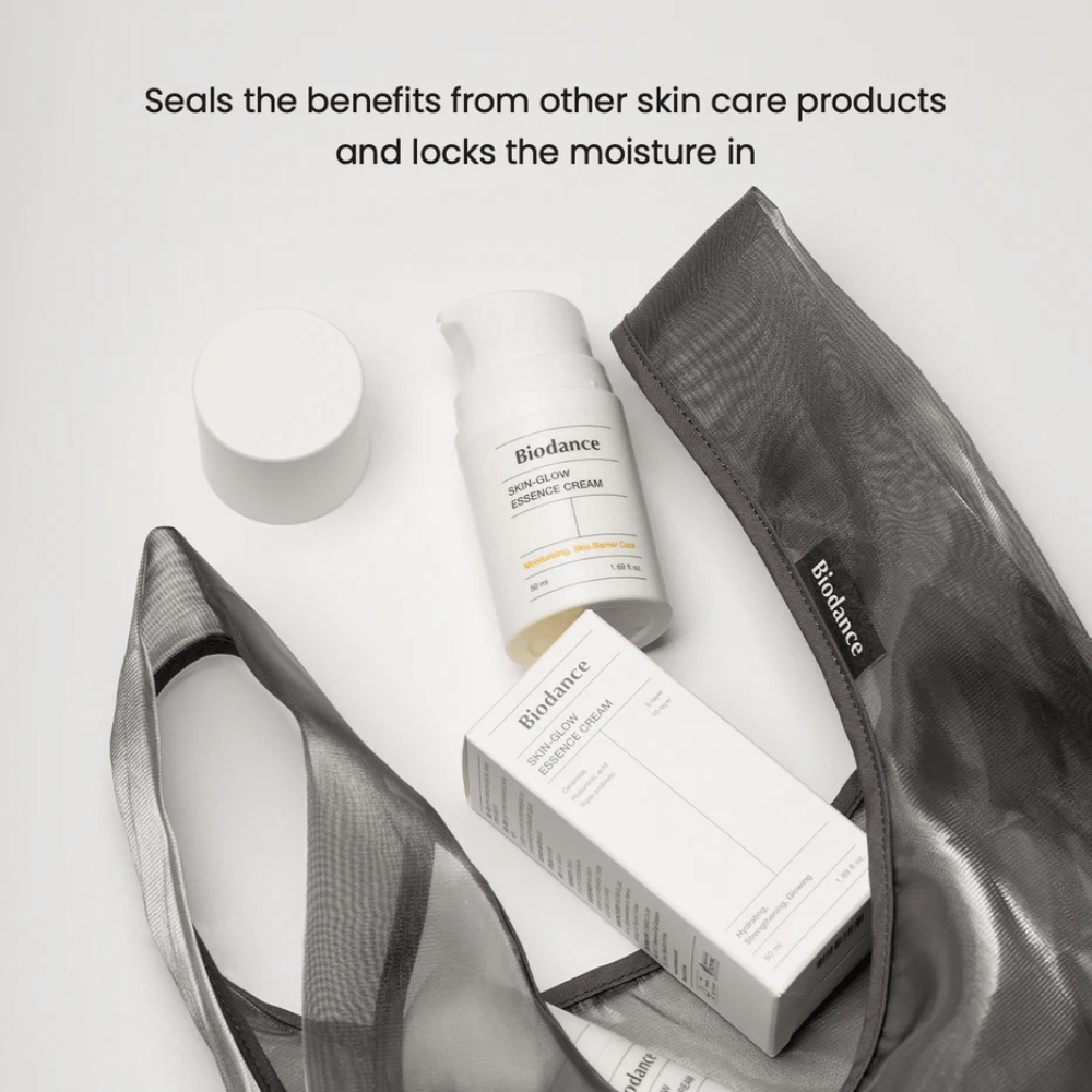 Biodance Skin-Glow Essence Cream stojący w centrum uwagi wraz z opakowaniem produktu i czarną przezroczystą kosmetyczką, z tekstem powyżej podkreślającym zdolność kremu do zatrzymywania wilgoci i wzmacniania efektu innych produktów do pielęgnacji skóry.