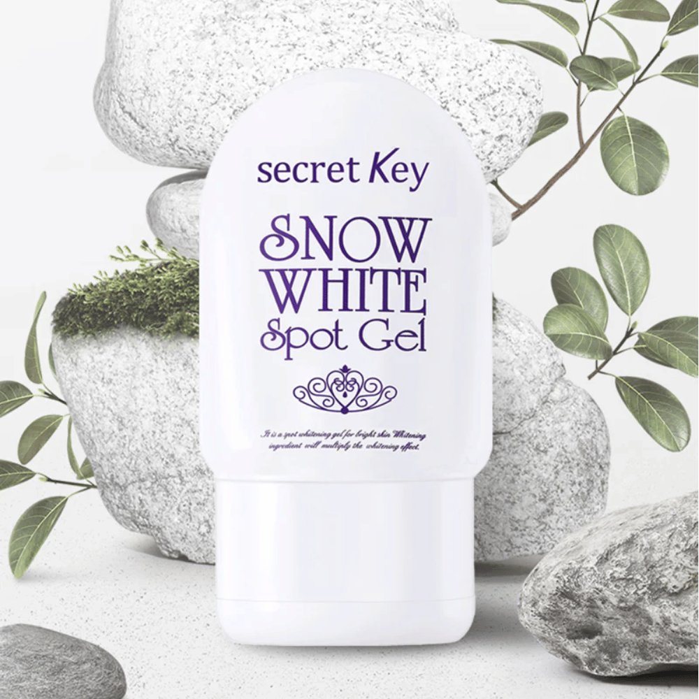 Secret Key Snow White Spot Gel sfotografowany na tle kamieni i zielonych liści.