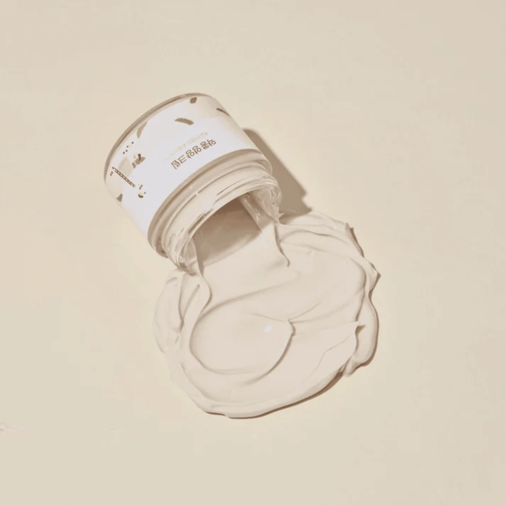 Mixsoon Soybean Nourishing Cream rozlany ze słoika na beżowym tle. Bogata konsystencja kremu pokazuje jego intensywne właściwości nawilżające.
