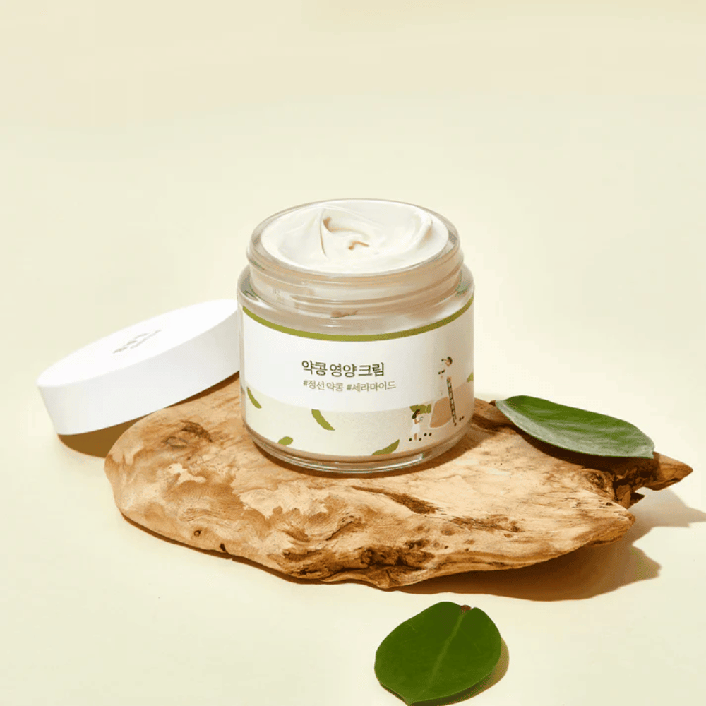 Mixsoon Soybean Nourishing Cream w otwartym słoiku na kawałku drewna z zielonymi liśćmi. Odżywczy krem z fermentowanymi sojami i ceramidami.