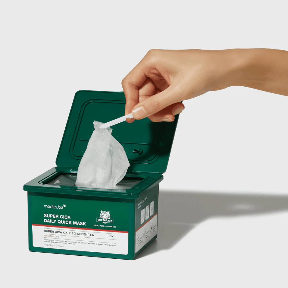 Zielony pojemnik z otwartą pokrywką pokazuje medicube Super Cica Daily Quick Mask. Ręka wyciąga maskę w płachcie za pomocą dołączonej pęsety. Produkt zawiera Cica, aloes i zieloną herbatę, idealny do szybkiego nawilżania i kojącego efektu.