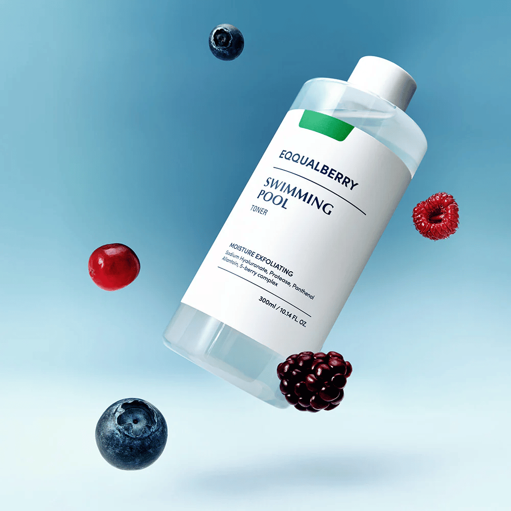 Equalberry Swimming Pool Toner w eleganckiej butelce unoszącej się na niebieskim tle, otoczonej świeżymi jagodami jak borówki, maliny i jeżyny.