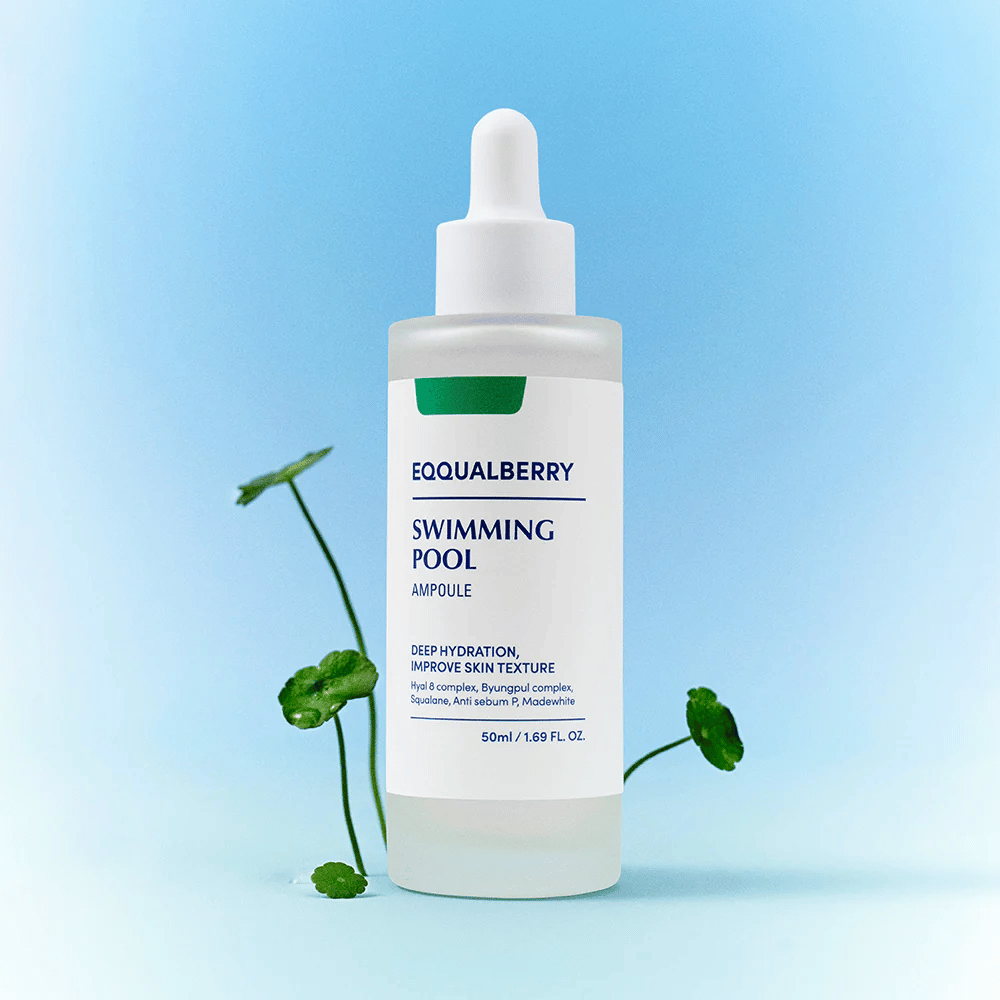 Butelka z Eqqualberry Swimming Pool Ampoule, produkt do pielęgnacji skóry o głębokim nawilżeniu i poprawie struktury skóry, umieszczona na jasnoniebieskim tle z kilkoma zielonymi roślinami na pierwszym planie.