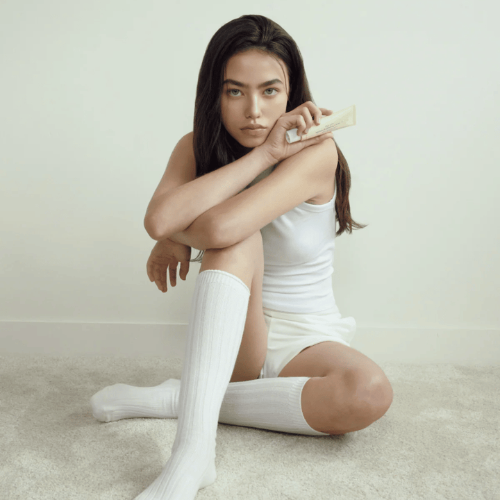 Zdjęcie lifestyle z modelką trzymającą produkt w jasnym i minimalistycznym otoczeniu. Obraz przekazuje czyste, naturalne i spokojne odczucie pielęgnacji skóry związane z efektem glow i rozjaśnienia.
