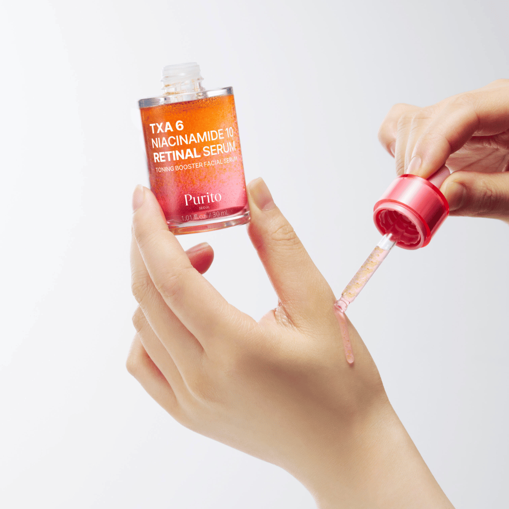 Ręka aplikuje Purito TXA 6 Niacinamide 10 Retinal Serum. Lekka formuła z aktywnymi składnikami dla blasku, elastyczności i jaśniejszej skóry.