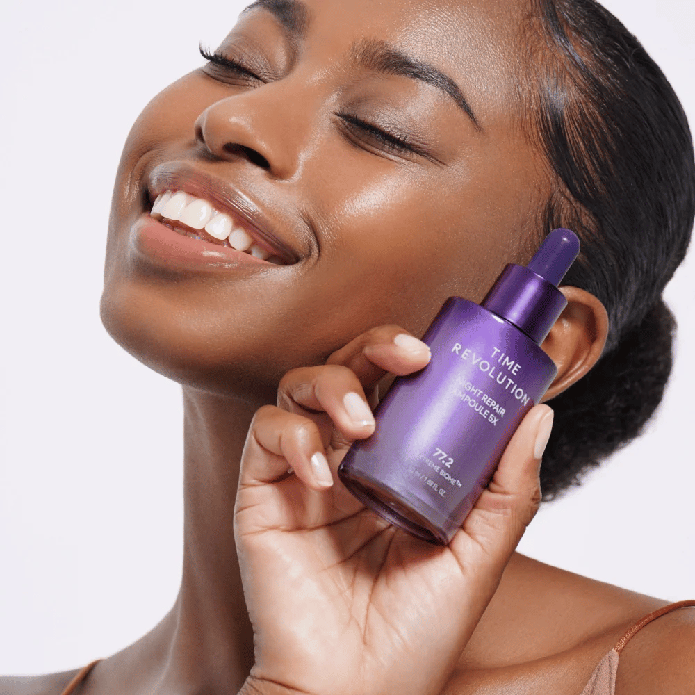 4. MISSHA Time Revolution Night Repair Ampoule 5X – modelka trzyma fioletowe serum na noc do pielęgnacji twarzy i blasku