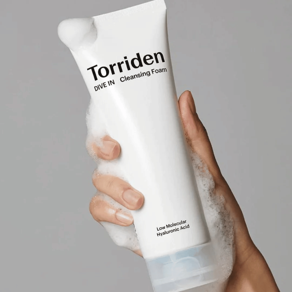 Ręka trzymająca tubę z pH-zbalansowanym Torriden DIVE-IN Low Molecular Hyaluronic Acid Cleansing Foam 150ml.