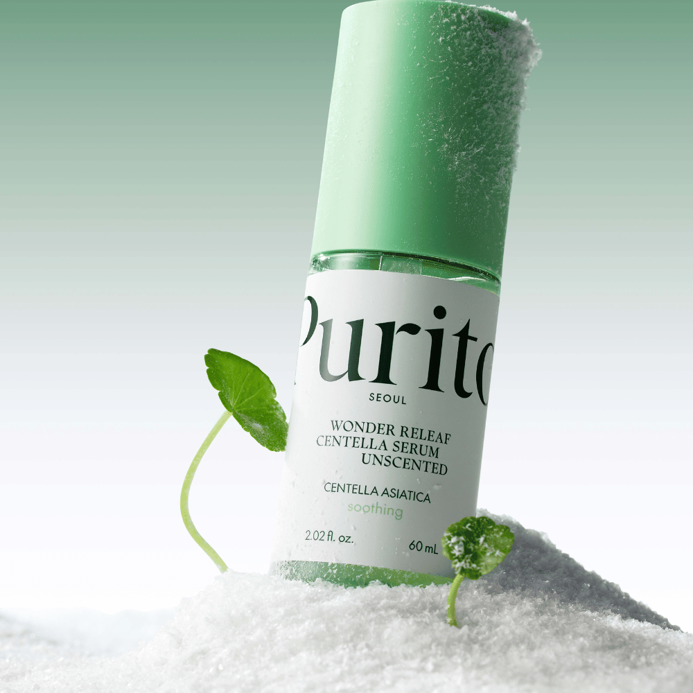 Butelka z Purito Centella Serum leży w śniegu, widoczne są zielone liście, na miękkim zielonym tle.