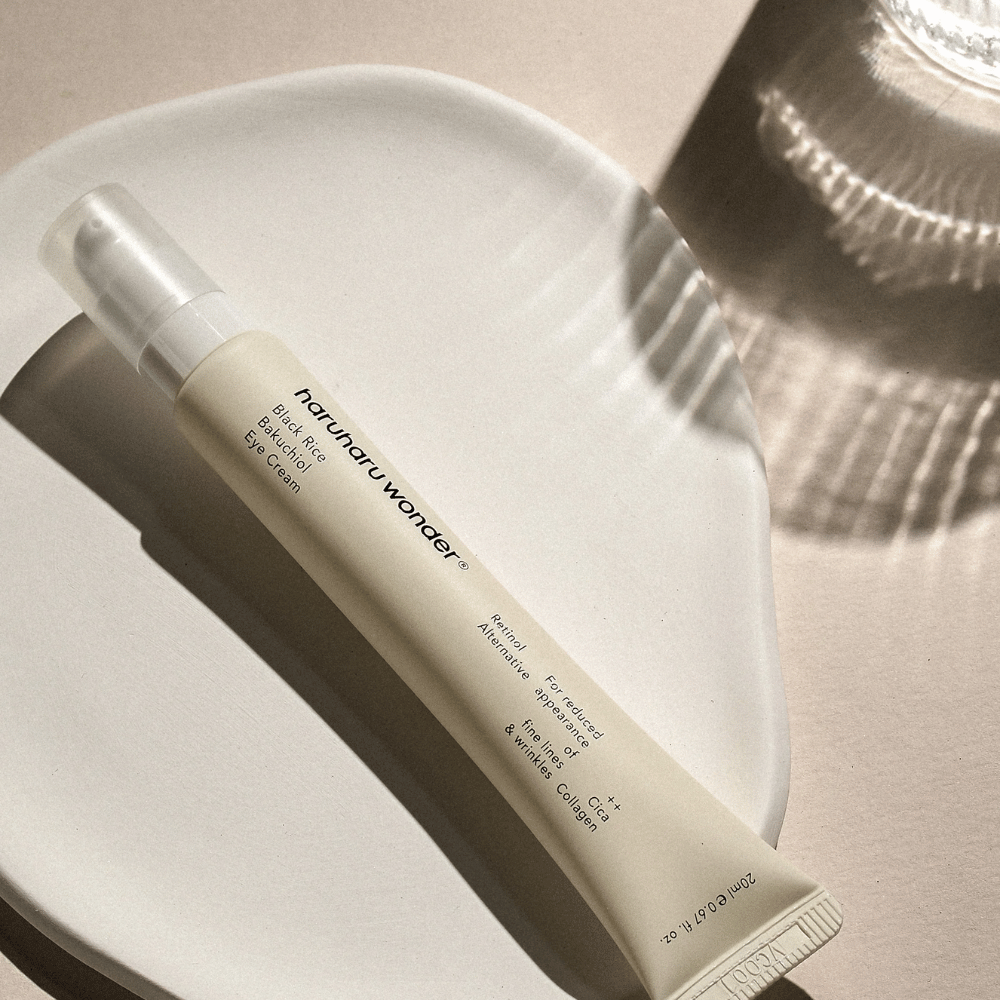 HaruHaru Wonder Black Rice Bakuchiol Eye Cream 20 ml – krem pod oczy z czarnym ryżem, bakuchiolem i kolagenem, który zmniejsza drobne linie i zmarszczki, umieszczony na ceramicznym talerzu w delikatnym świetle.