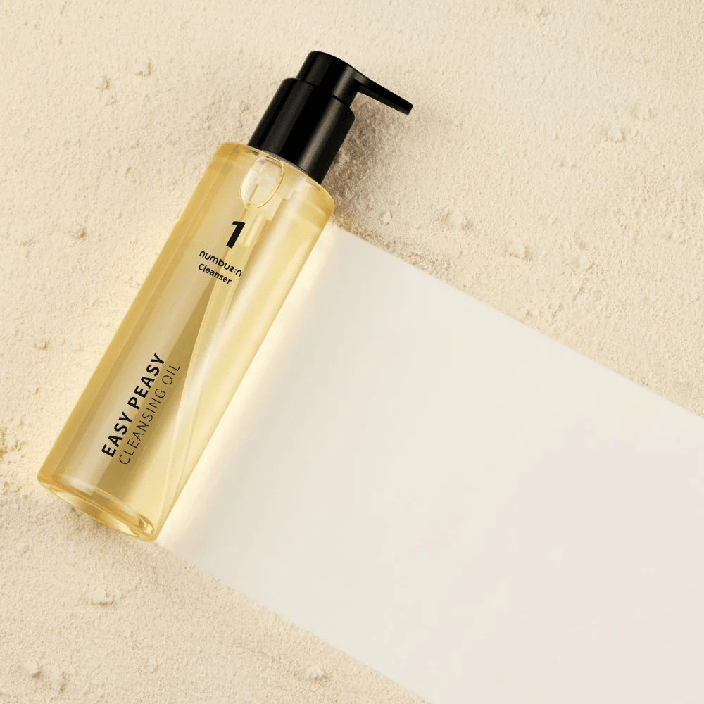 Numbuzin No.1 Easy Peasy Cleansing Oil liggande på sandfärgad yta med skugga.