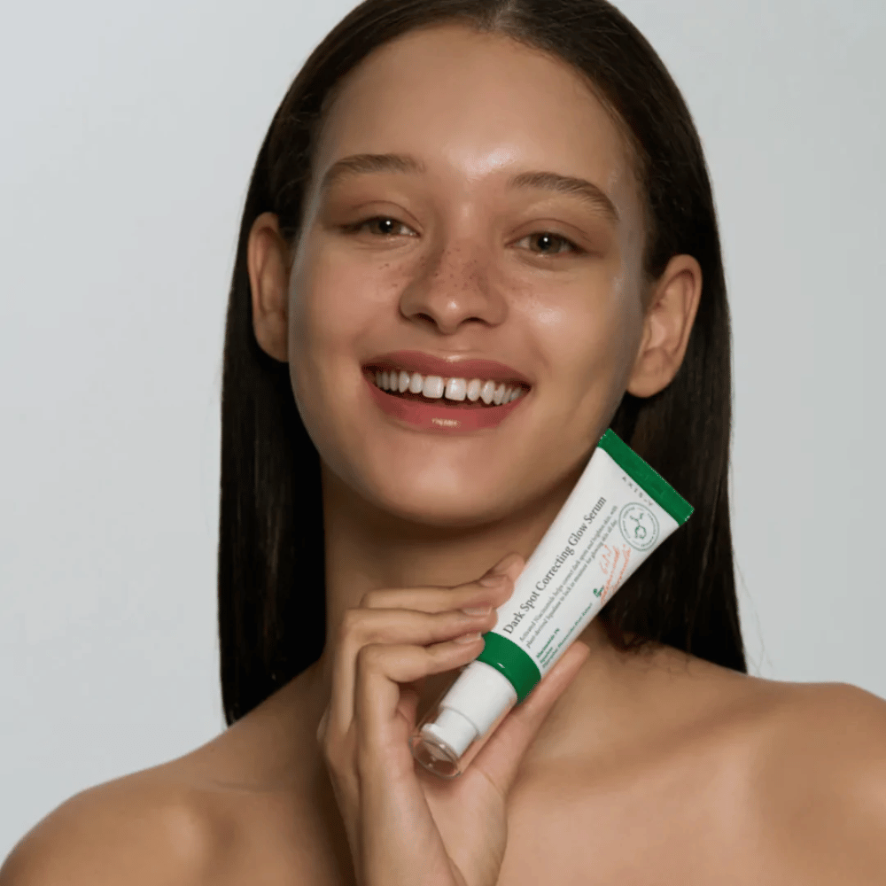 Młoda kobieta trzyma tubę AXIS - Y Dark Spot Correcting Glow Serum 50ml.