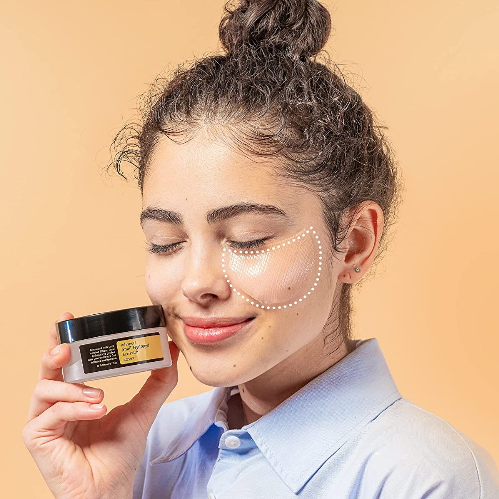 Kobieta trzymająca słoik COSRX Advanced Snail Hydrogel Eye Patch 60 sztuk kremu do twarzy.