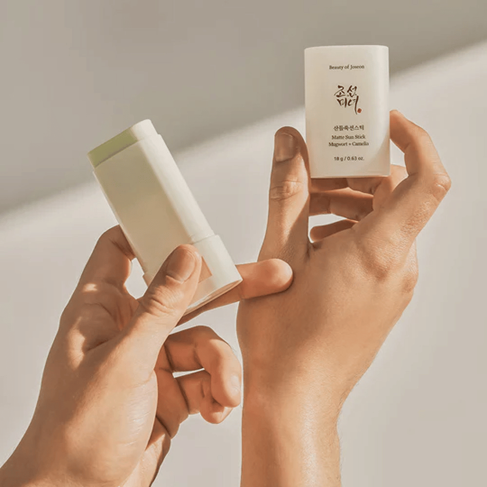Dwie ręce trzymające sztyft Beauty of Joseon's Matte Sun Stick 18g SPF50 PA++++.