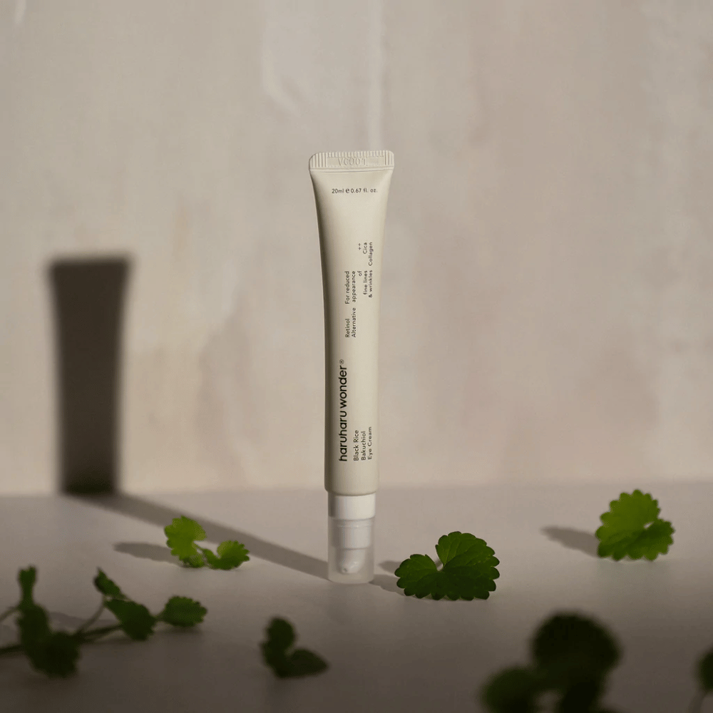 Tubka Haruharu Wonder Black Rice Bakuchiol Eye Cream 20ml otoczona zielonymi liśćmi, skoncentrowana na widoczności zmarszczek i drobnych linii.