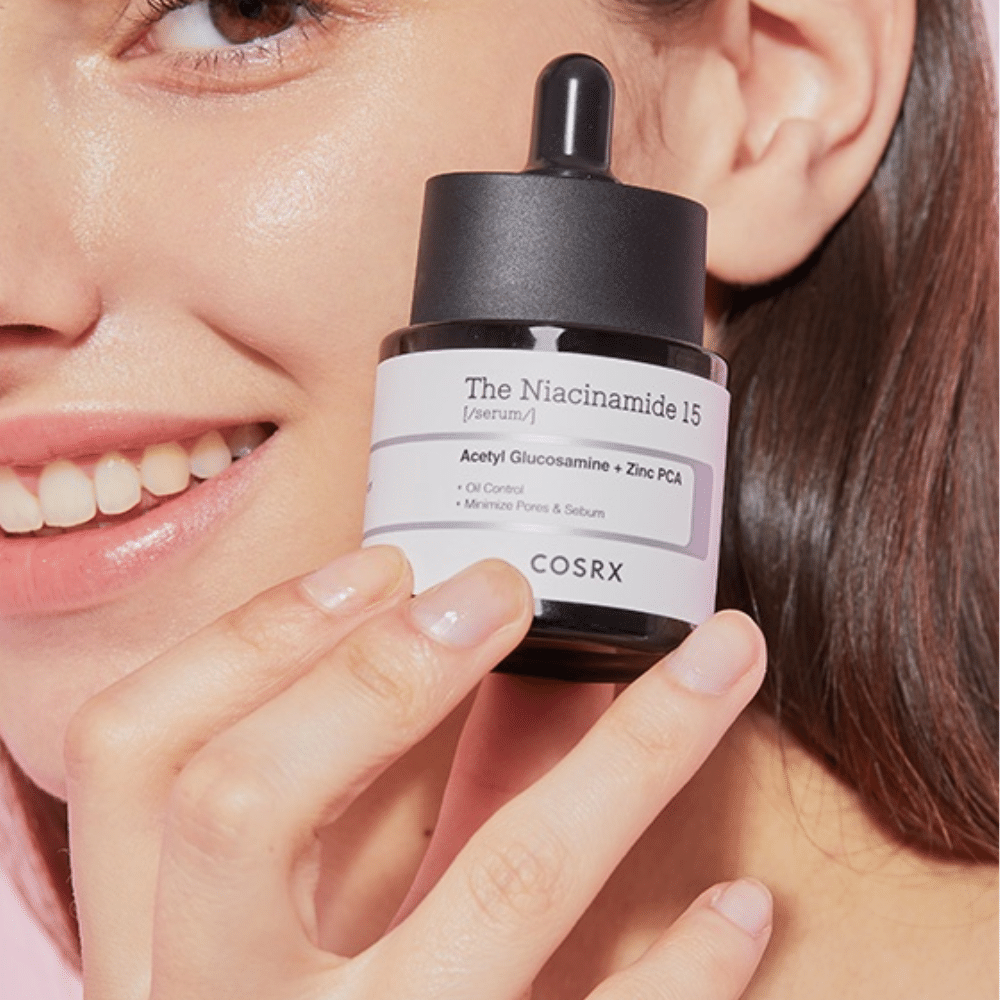 Kobieta trzyma butelkę COSRX Niacinamide 15 Serum 20ml dla niacynamidu i produkcji sebum.