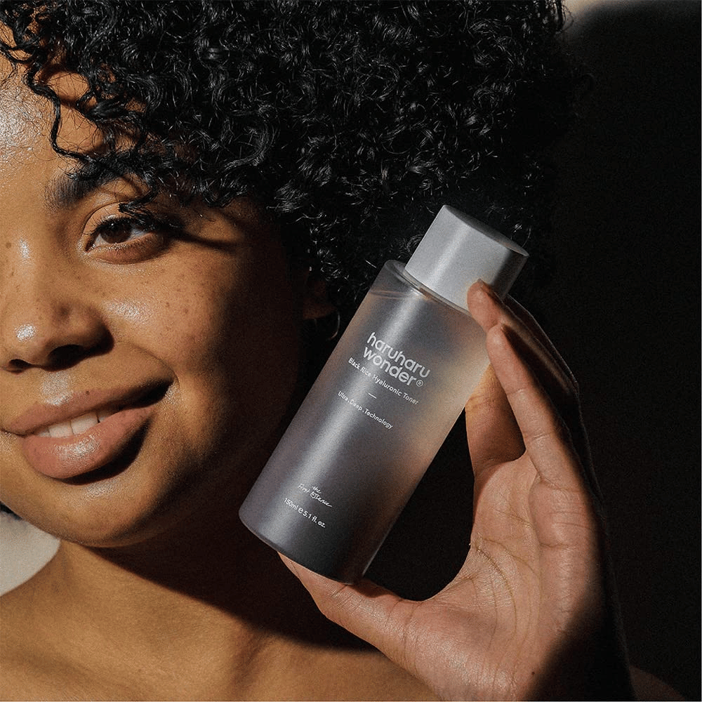 Kobieta trzymająca butelkę Haruharu Wonder Black Rice Hyaluronic Toner Original 150 ml.