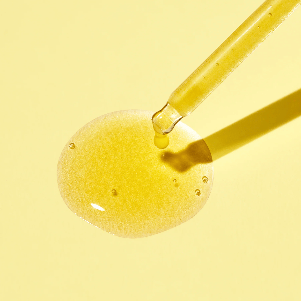 Kropla płynu na żółtym tle, z MISSHAs Vita C Plus Spot Correcting & Firming Ampoule.